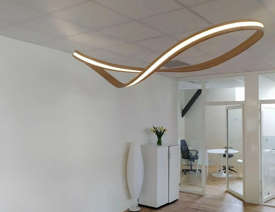 Bureau moderne avec éclairage LED architectural suspendu formant des courbes dorées lumineuses