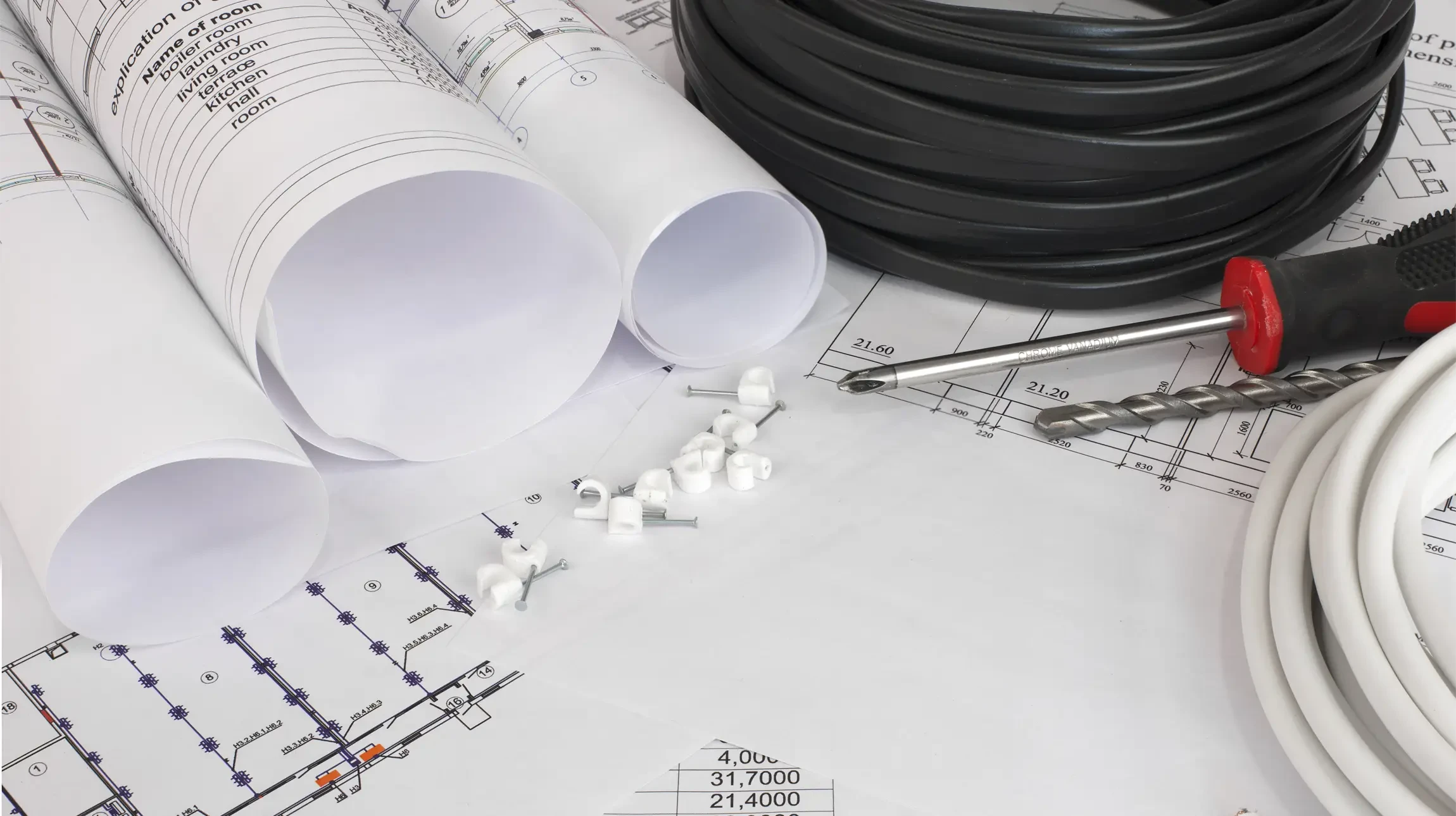 Une personne dessine sur des plans d'architecture avec un crayon mécanique dans un bureau moderne