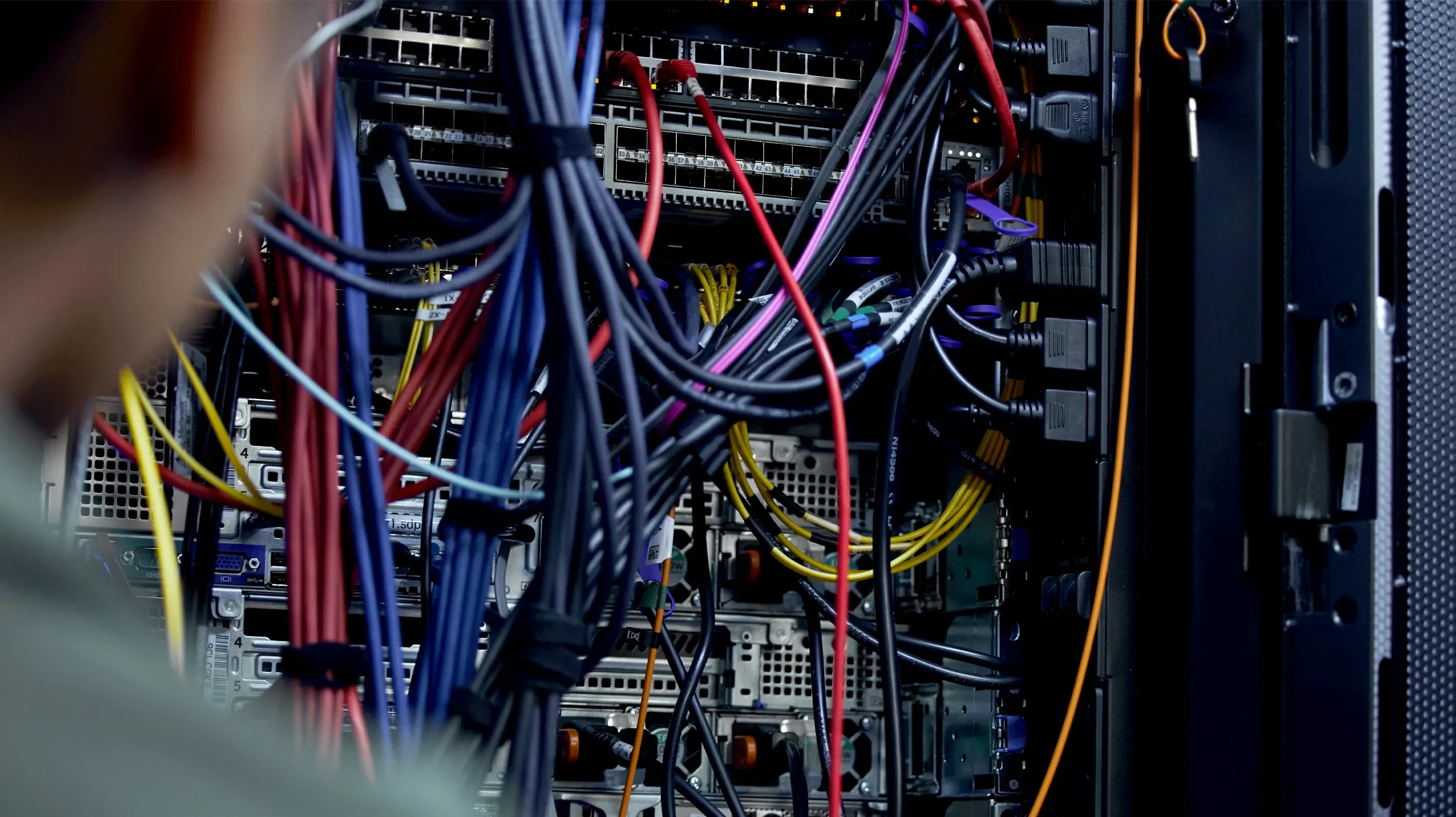 Scène en intérieur montrant des câbles réseau ethernet bleus alignés en perspective, photographiés en macro avec éclairage LED bleu créant une ambiance technologique